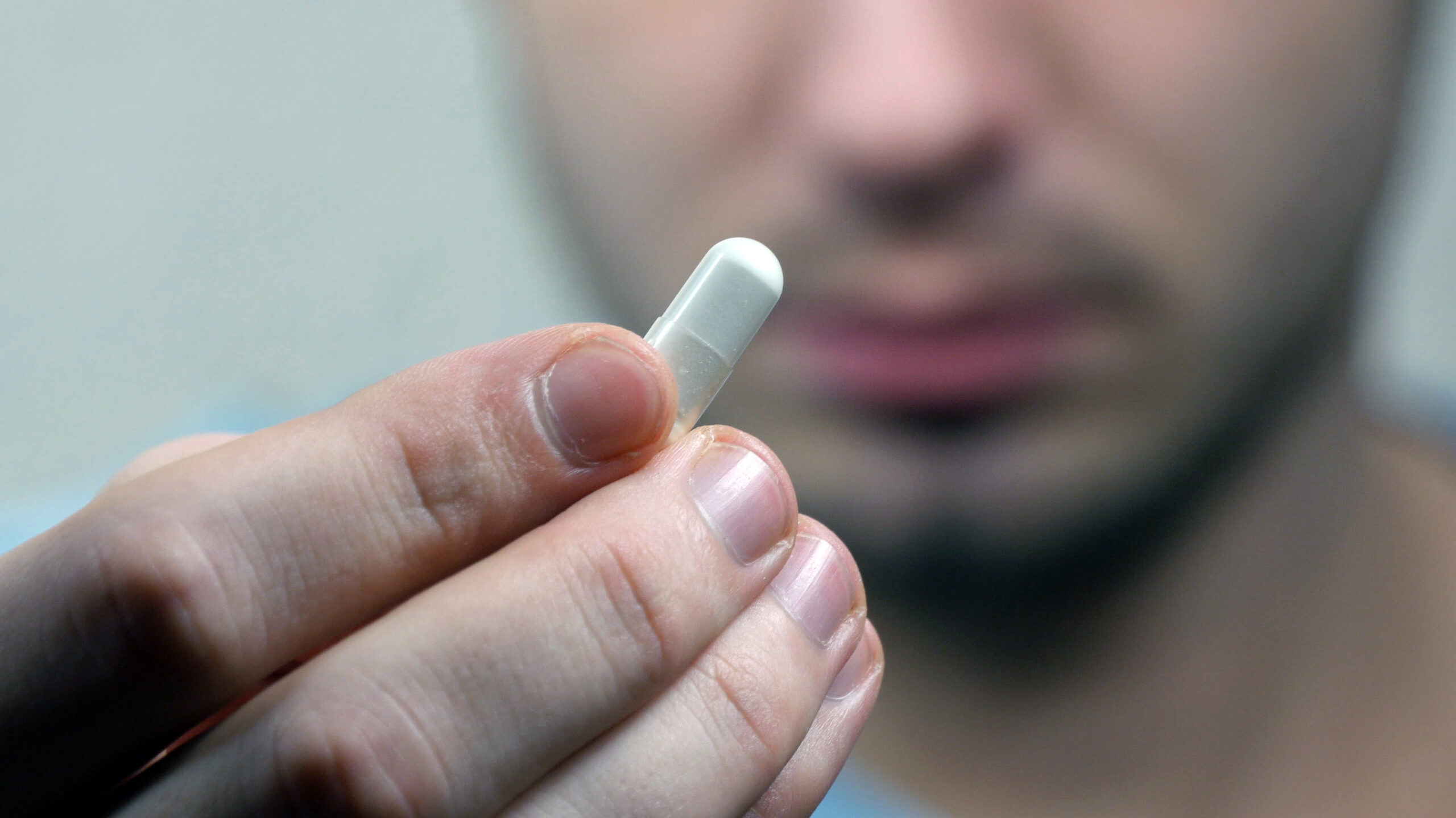 man holding a white pill in his hand
