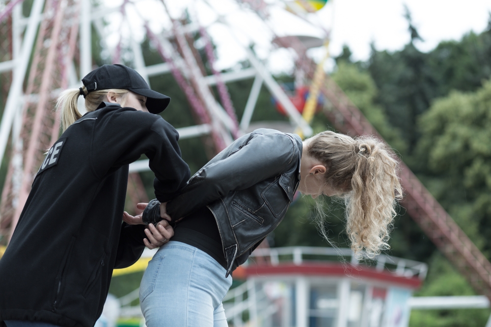 Female officer arresting woman in an aggressive manner.