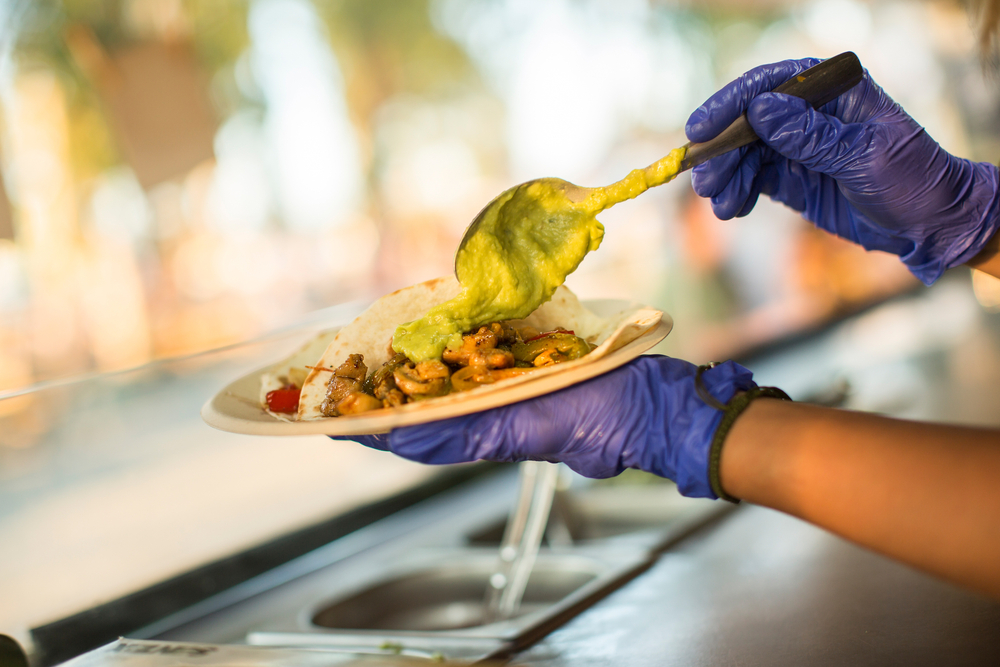 person preparing a plate of tacos on food truck