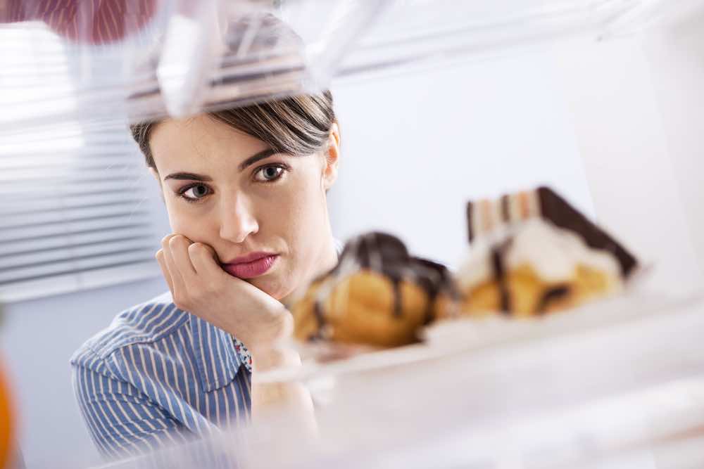 Woman looking at pastries in refrigerator