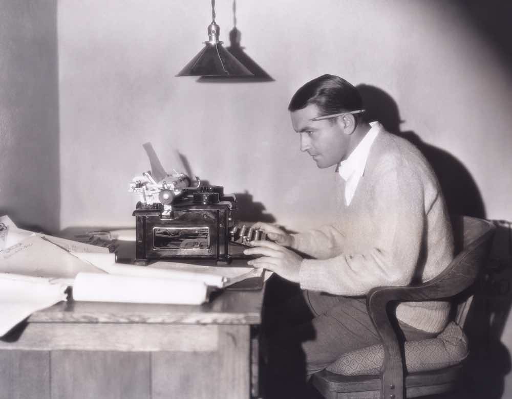Black & white image of man working at typewriter
