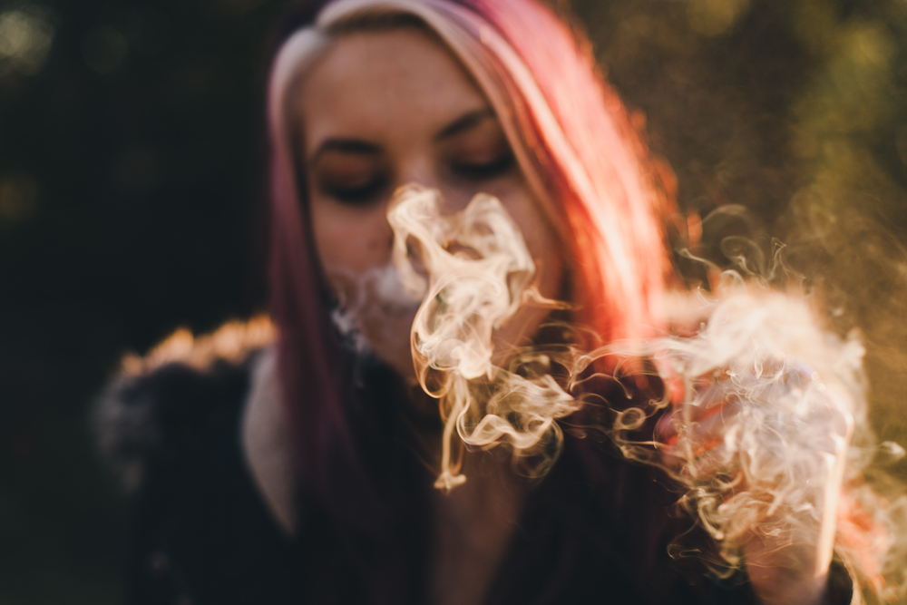 pink haired woman smoking in the sun