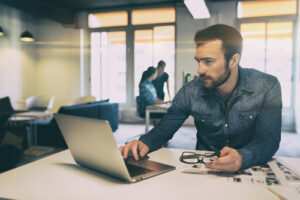 Man in modern office start-up working on laptop.