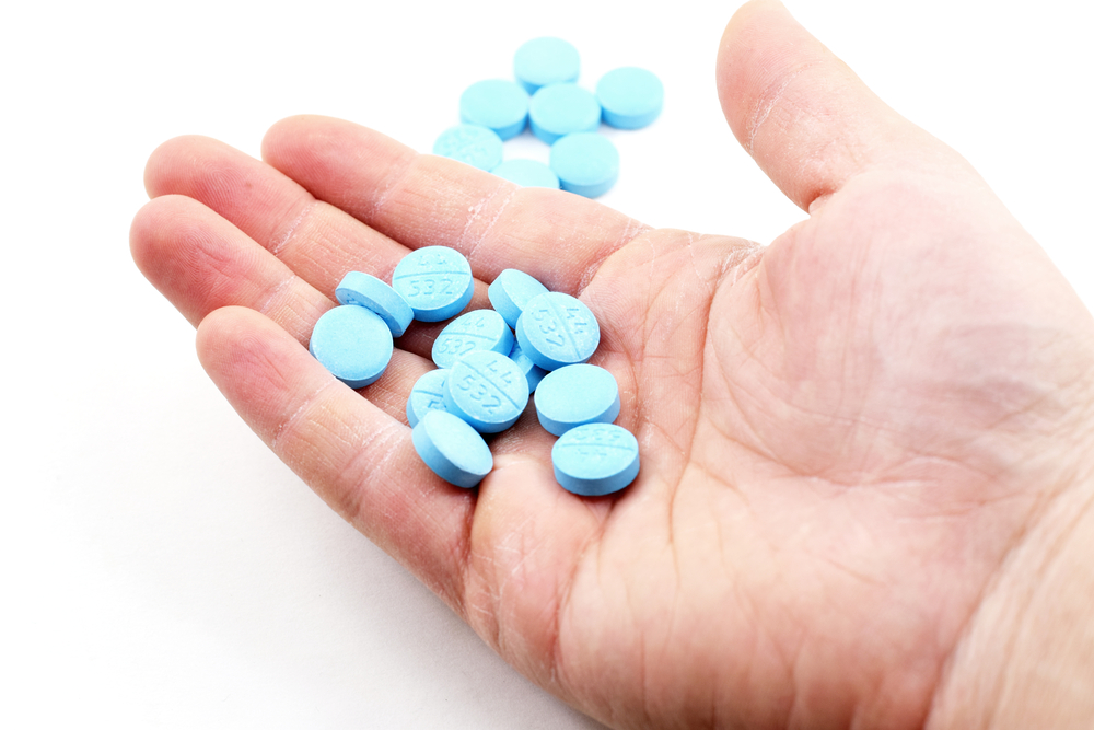 a hand holding a pile of blue pills.