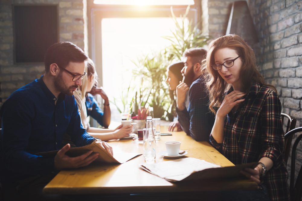 People sitting at a long table, talking and drinking.