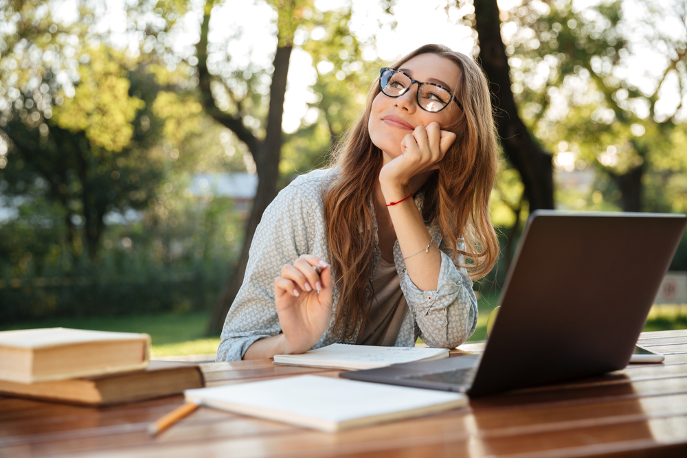 happy woman sitting at table in park
