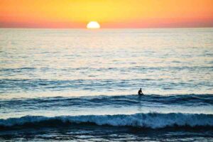 silhouette of person in ocean with sunset.