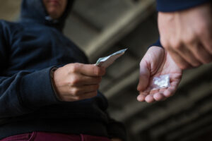 a person purchasing pills illegally from another person in a hoodie.