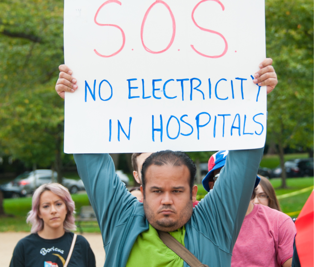man holding a sign about power outages in Puerto Rico after Hurricane Maria