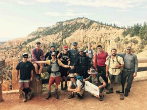 A group of men in hiking gear with mountains in the background.