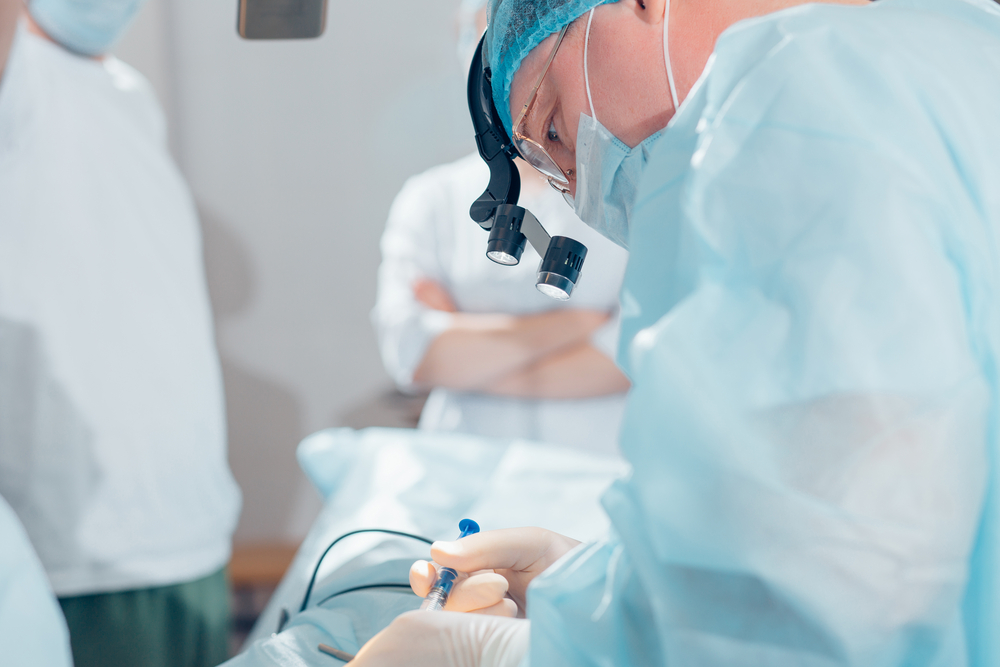 Surgeon performing cosmetic surgery on nose in hospital operating room.