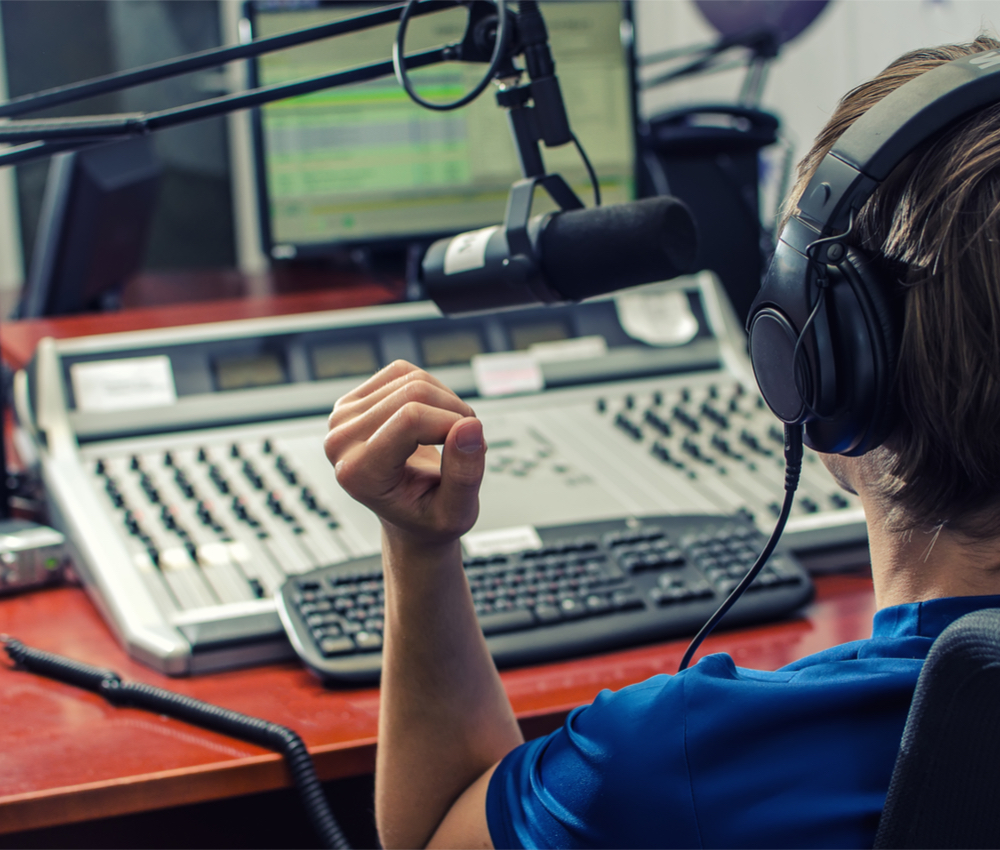 Dj working in front of a microphone on the radio, from the back