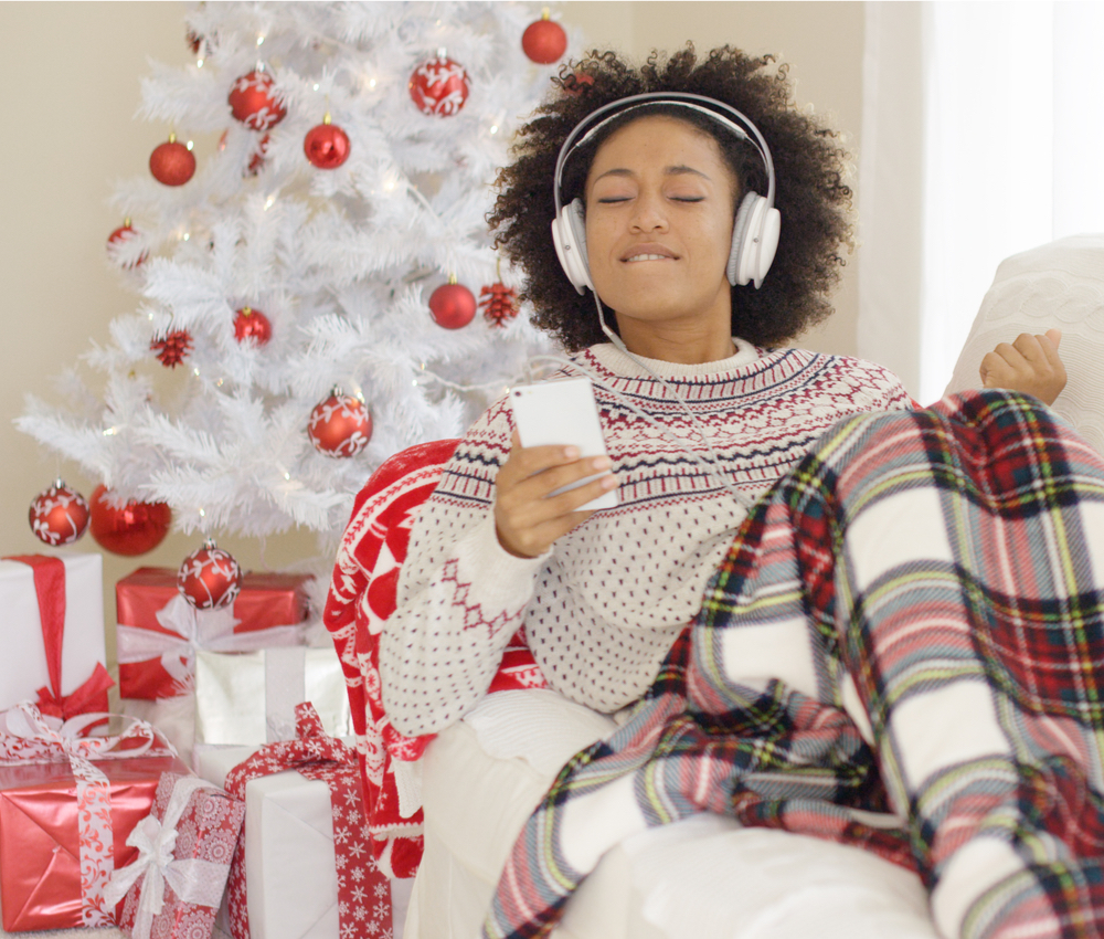 woman wearing headphones listening to music with Christmas tree in background