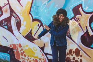A woman smiling in front of a graffiti'd wall