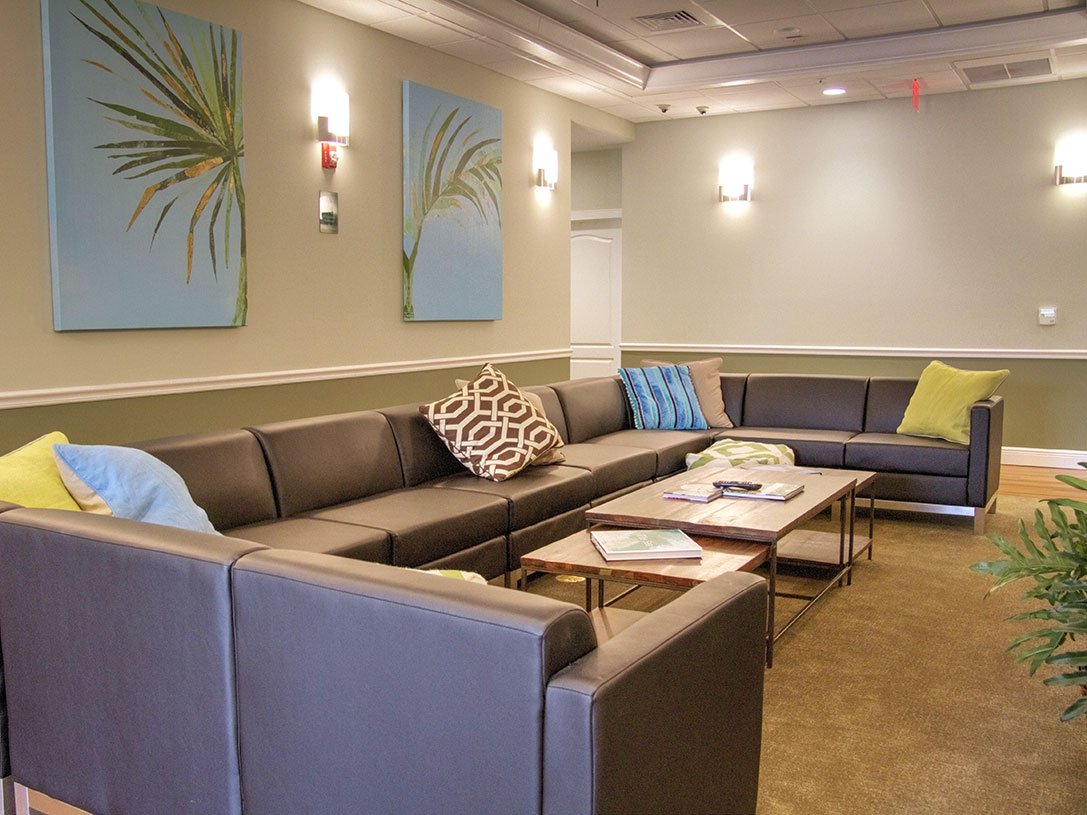 A living room with large couch, lights, and art on the walls.