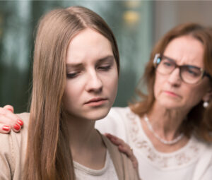 Supportive mother helping her worried teenage daughter