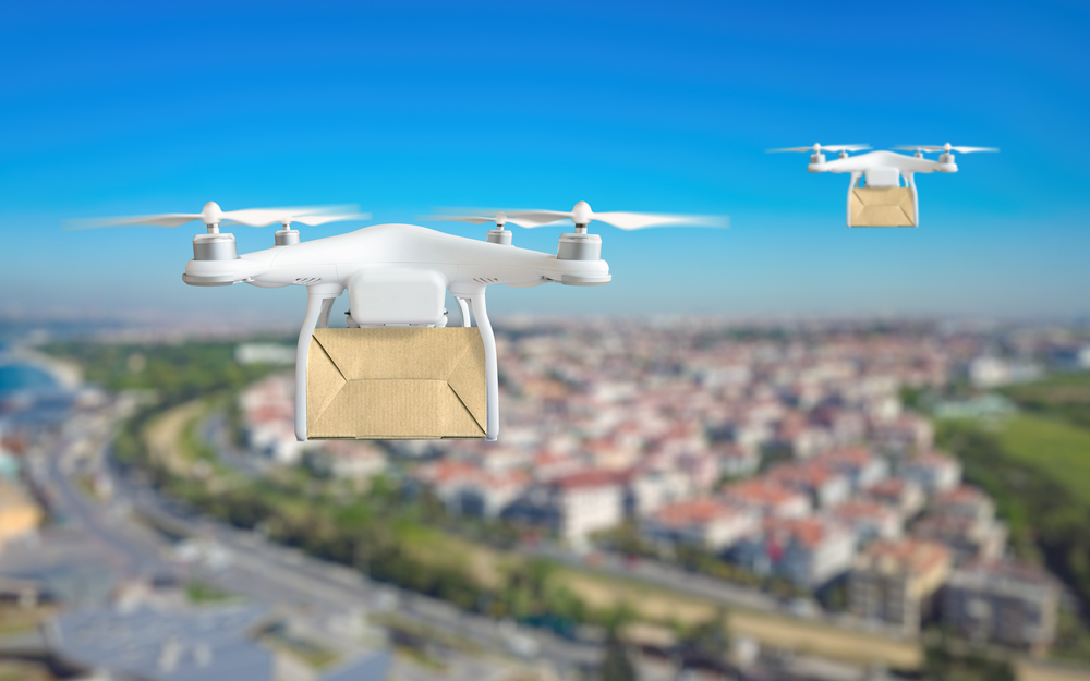 Modern technological delivery innovation - drone fast delivery concept, two multicopters flying with cardboard box above city