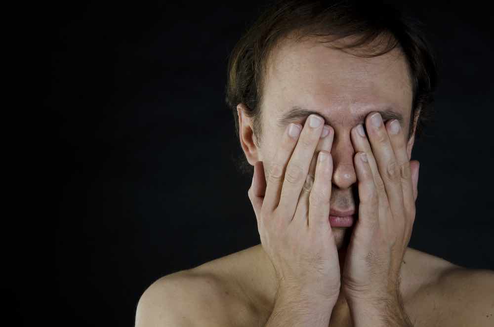 Man with hands over his eyes.