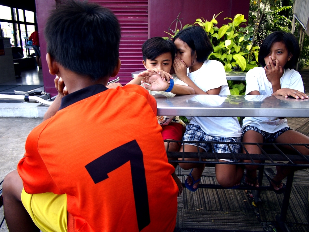 Young children relaxing at an outdoor park bench in the Philippines.
