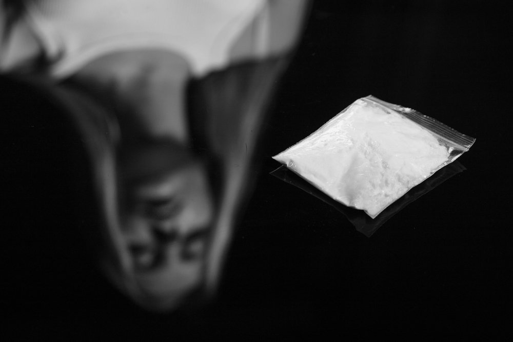 woman looking at baggie of drugs