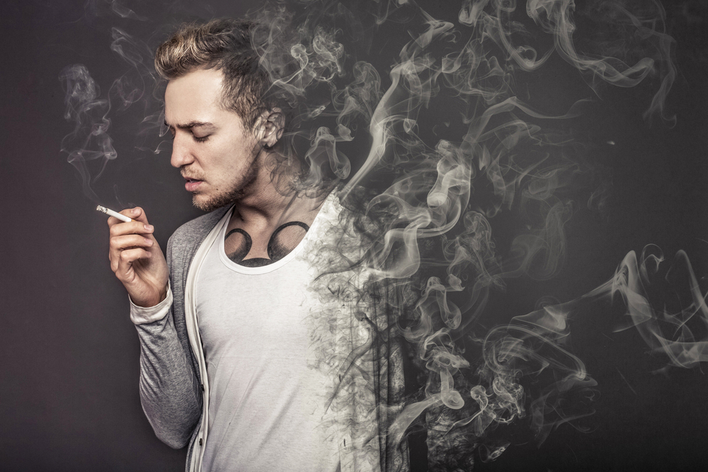 Tatted man smoking a cigarette and dissolving into smoke.