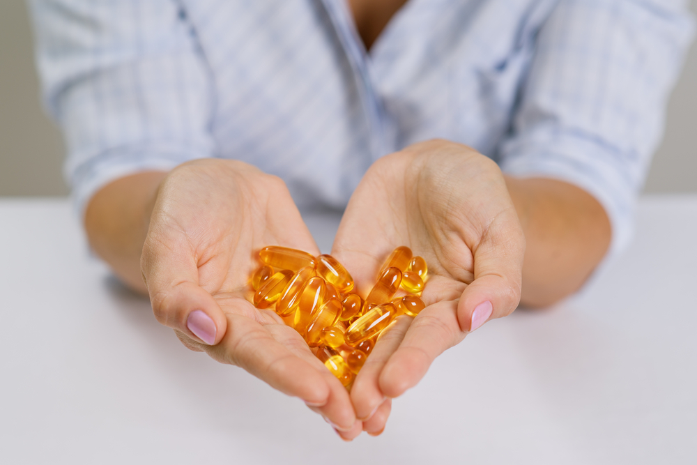 woman holding a handful of orange supplement pills