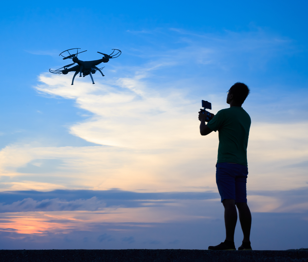 Silhouette of a man using drone outdoor with sunset