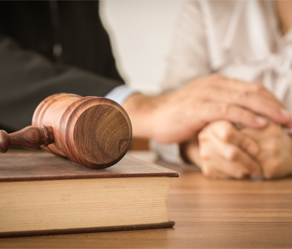 Judge gavel, man and woman in background consoling each other