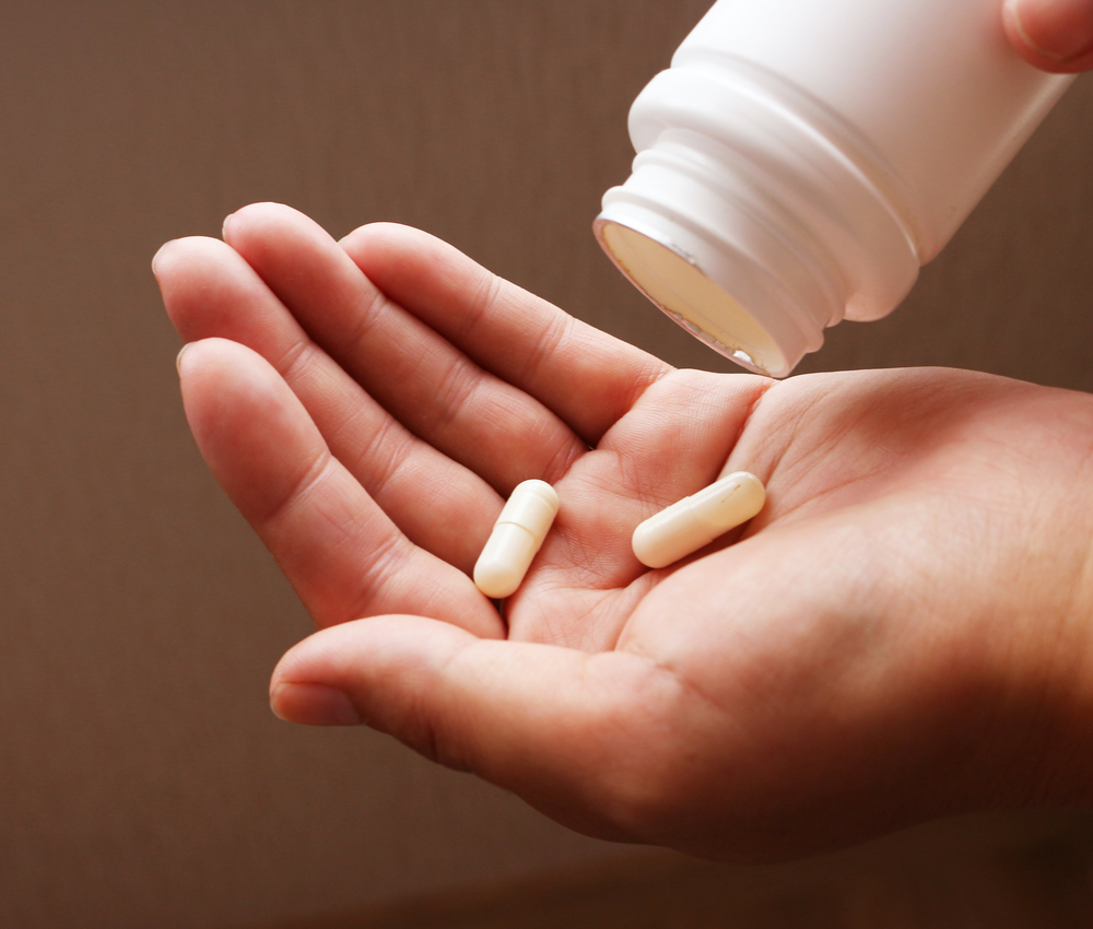 woman pours pills out of the bottle and into her hand