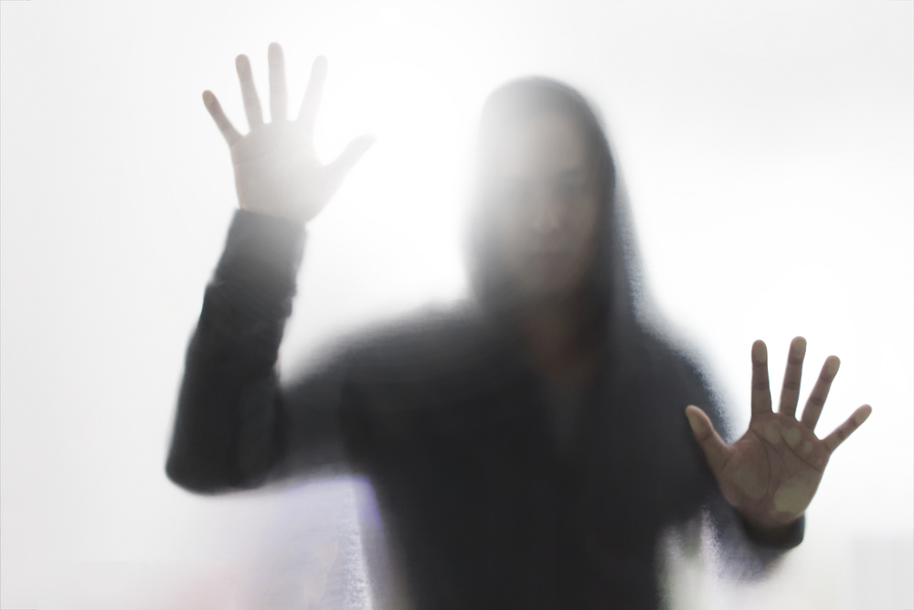 A person reaching out, trapped behind a blurred screen