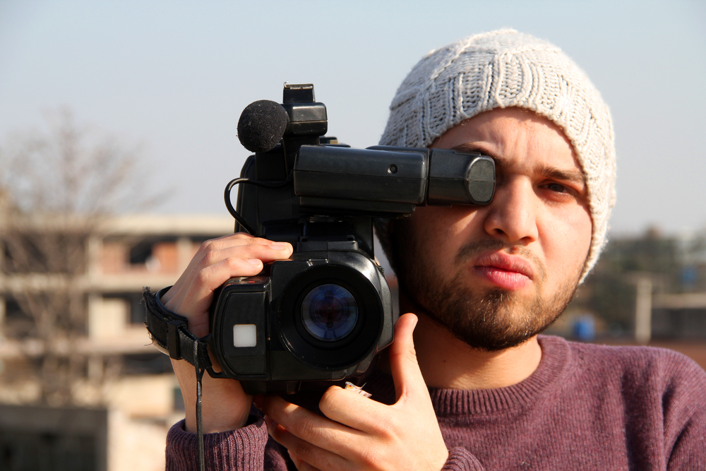 Young man holding a video camera to his eye