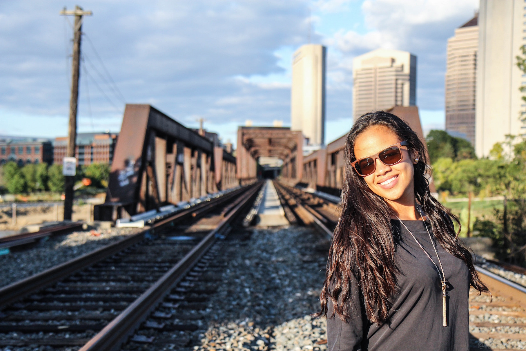 A smiling woman in front of a train track.