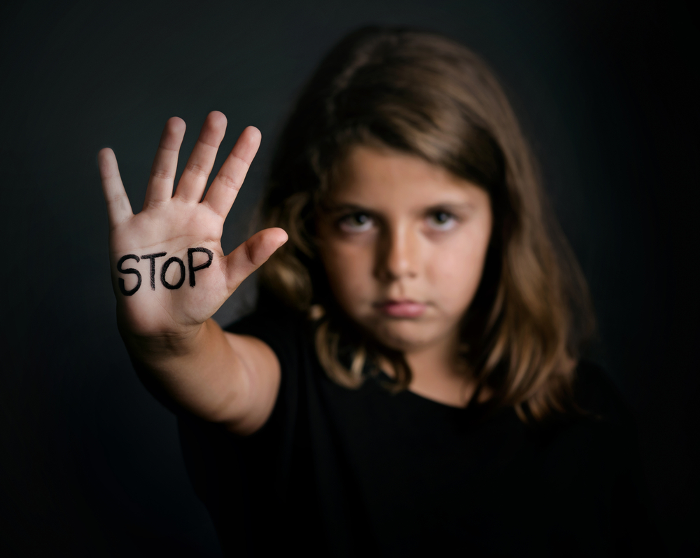 A little girl with her hand out in front of her, on which is written "stop"