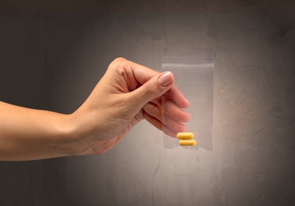 hand giving drugs in plastic bag