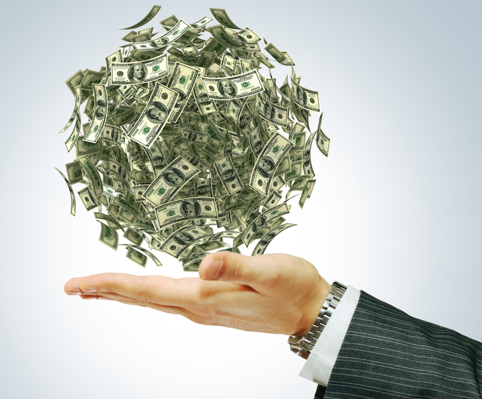 a ball of money sitting atop a businessman's hand.