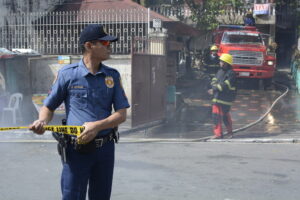 SAN PABLO CITY, LAGUNA, PHILIPPINES - MARCH 7, 2017: Police officer help maintain order during house fire that gutted interior shanty houses
