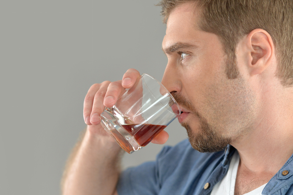 man drinking from a glass of alcohol