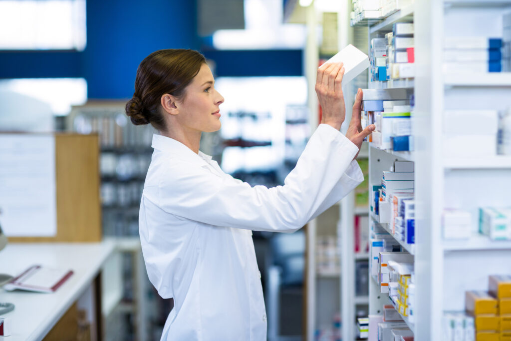 Pharmacist checking medicine on shelf at pharmacy