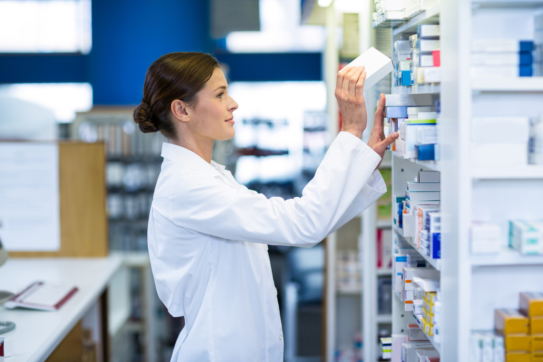 Pharmacist checking medicine on shelf at pharmacy