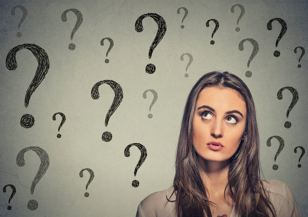 woman looking up at many question marks