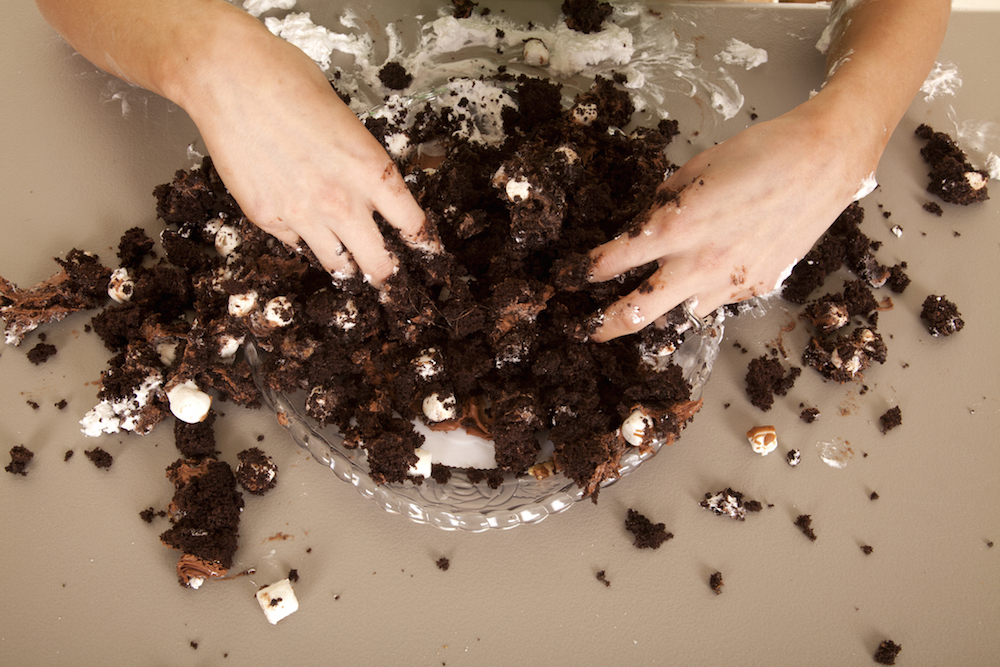 woman destroying chocolate cake with hands