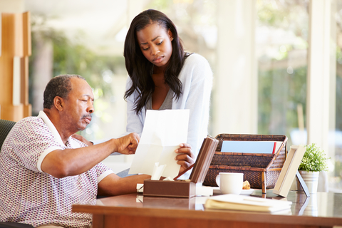 Adult daughter with senior father discussing document.