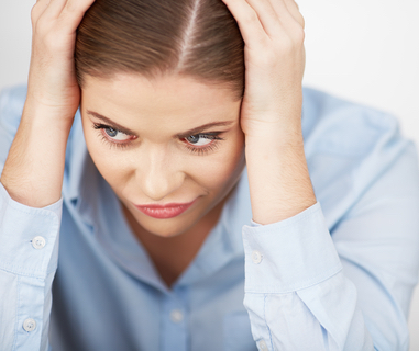 A woman has her head in her hands, looking stressed.