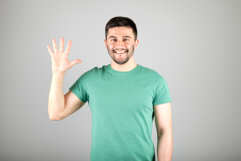 A man holding up one hand with fingers spread (indicating 5)