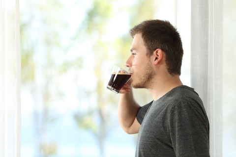 Man drinking coffee at window.