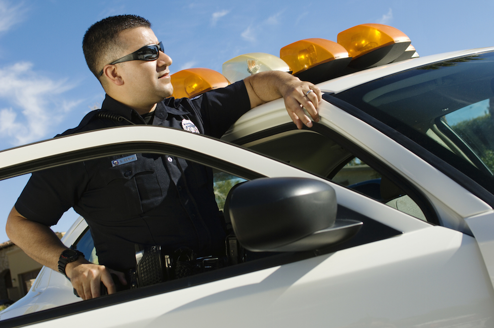 Police Officer Leaning On Patrol Car