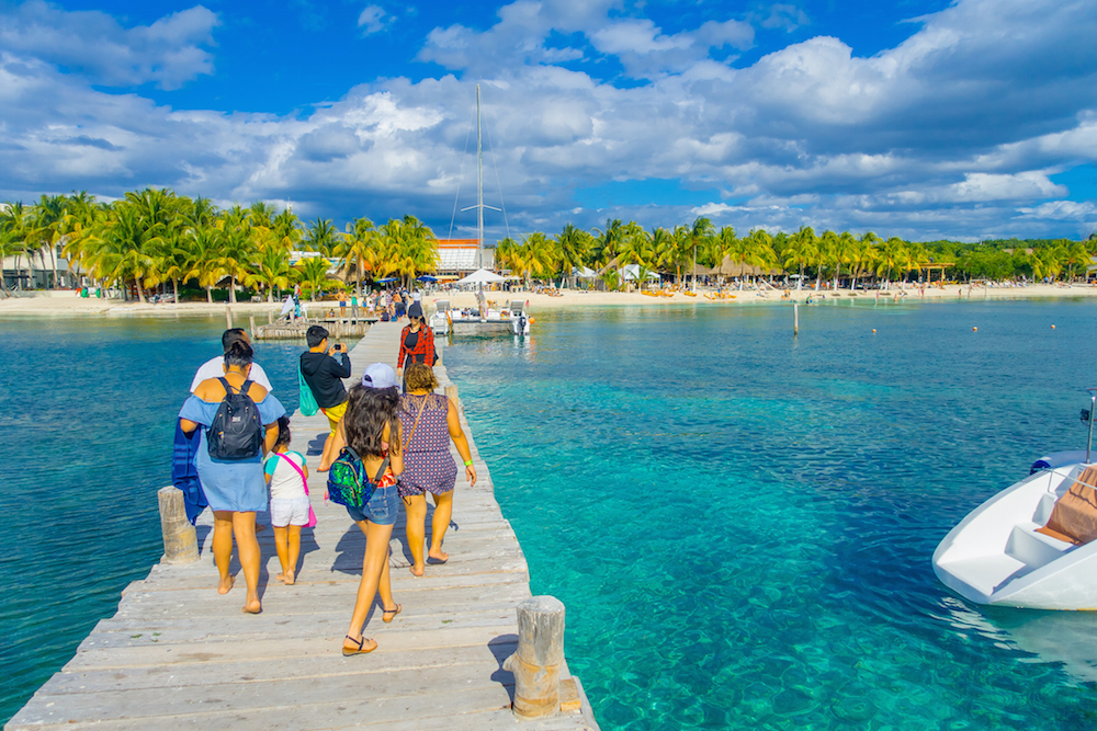 tourists walking over a wooden pier in Cancun