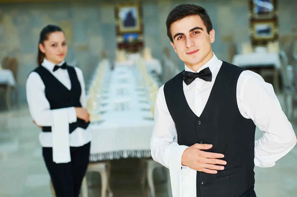 Two waiters in black and white uniforms preparing for service
