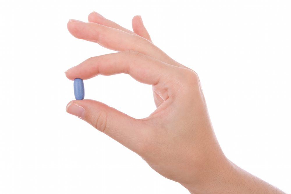 hand holding a blue pill