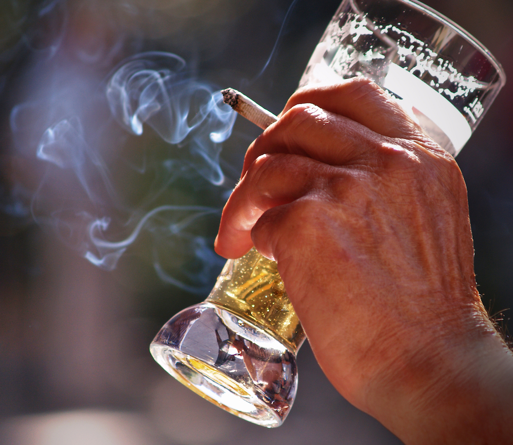 hand holding a beer and a cigarette
